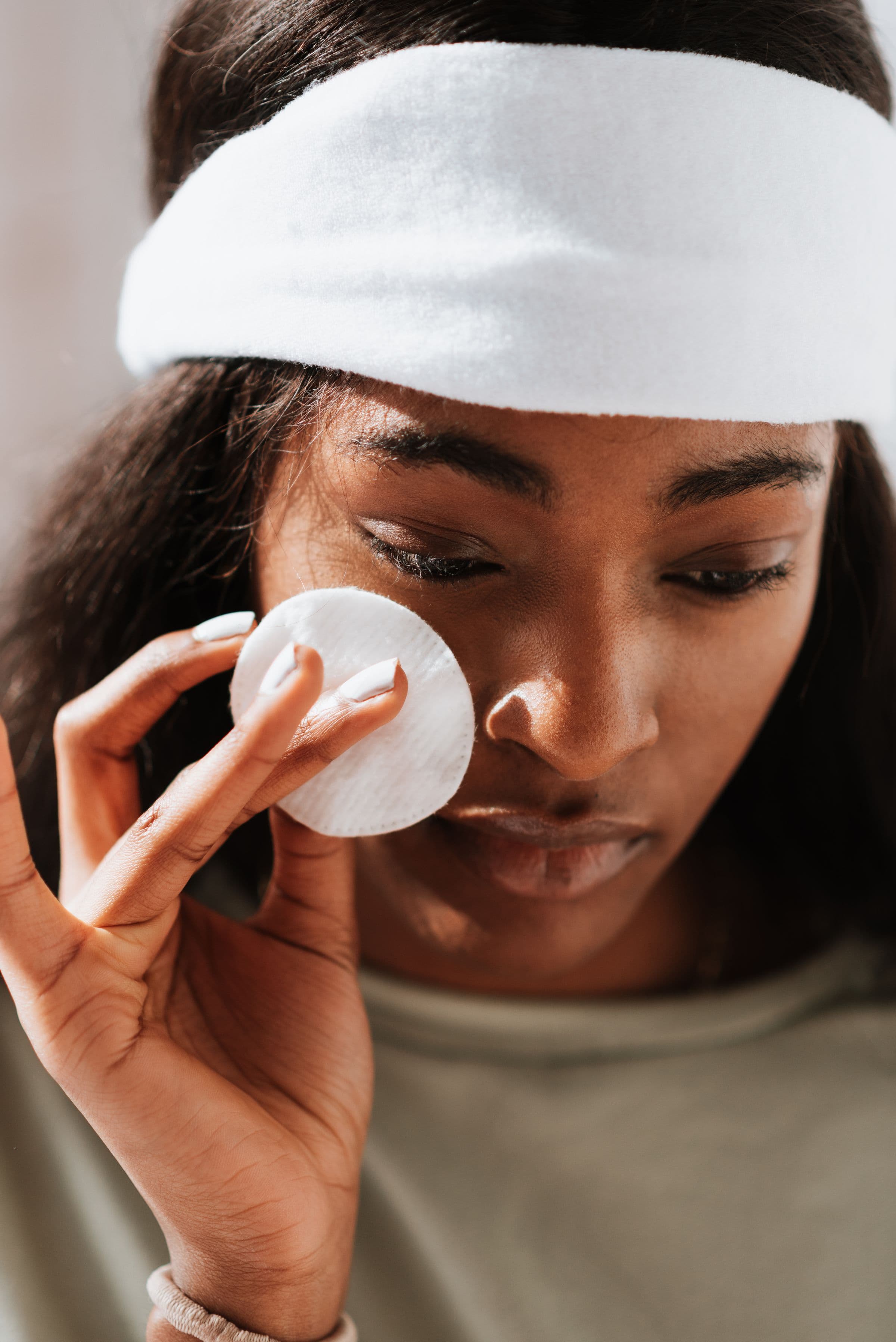 A woman cleansing her face in window light